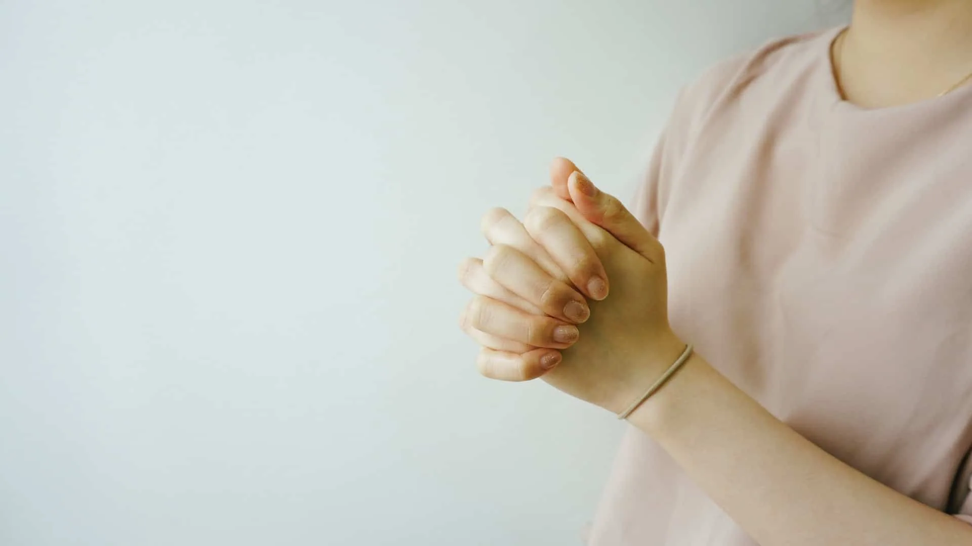 祈りのために手を握る女性